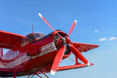 Red airplane with a propeller against the sky