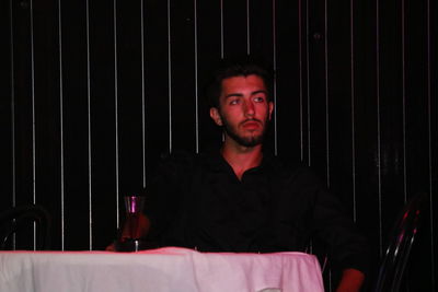 Thoughtful young man having drink while sitting at table in restaurant