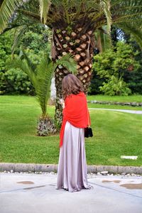 Rear view of woman standing by palm trees