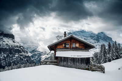 House on snow covered mountain against sky