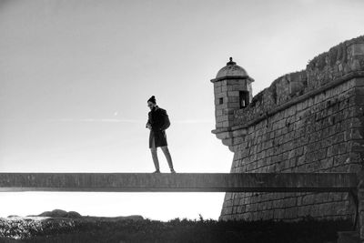 Man standing on built structure against clear sky