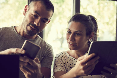 Male showing mobile phone to female partner in cafe