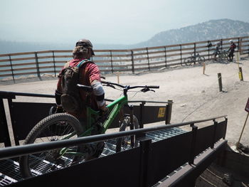 Rear view of man with bicycle walking on steps