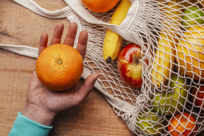 High angle view of hand holding orange