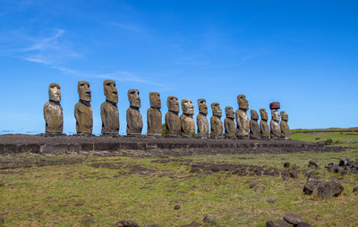 People walking on field against clear blue sky