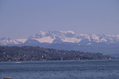 Scenic view of sea by mountains against clear sky