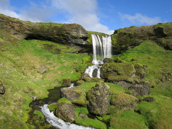 Low angle view of waterfall on mountain against sky