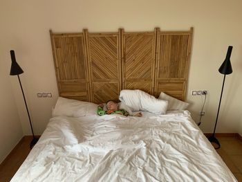 High angle view of boy sleeping on bed against wall at home