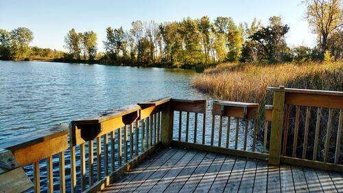 Pier over lake against clear blue sky