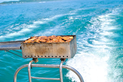 Close-up of metallic container on shore against blue sea