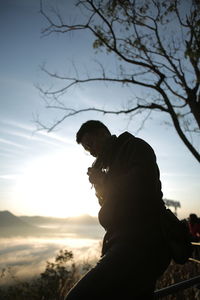 Side view of young man standing against sky during sunset