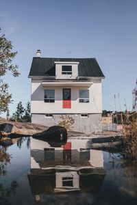 Reflection of building in lake against clear sky