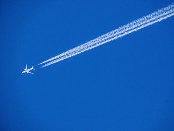 Low angle view of airplane flying in blue sky