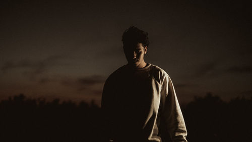 Silhouette man looking at camera against sky during sunset