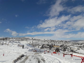 People on snow covered landscape against sky