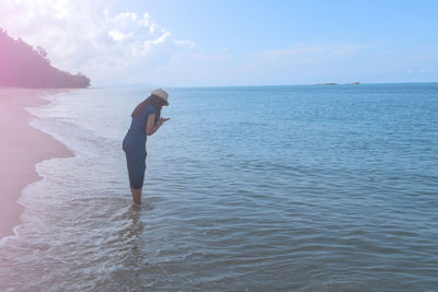 Side view of man standing on beach against sky