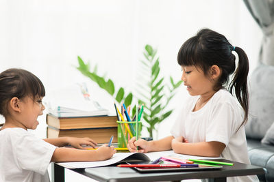 Rear view of siblings sitting on table
