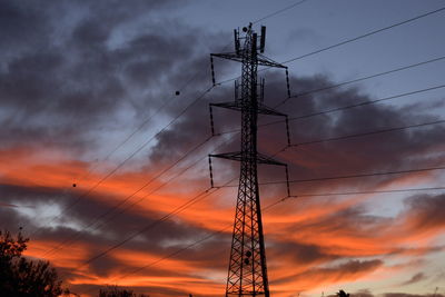 Low angle view of silhouette electricity pylon against sky during sunset