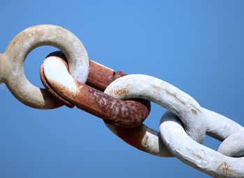 Low angle view of rusty metallic chain against clear sky