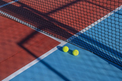 Two balls near the net of a red tennis court