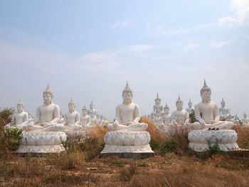 Buddha statues against sky on field