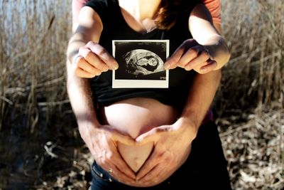 Midsection of woman holding hands on field