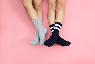 Low section of children wearing socks while resting over colored background