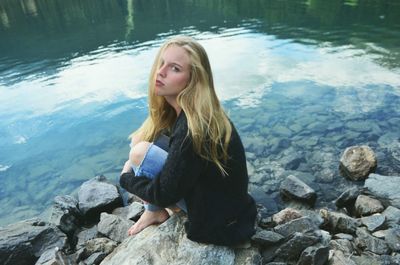 Young woman sitting on lakeshore