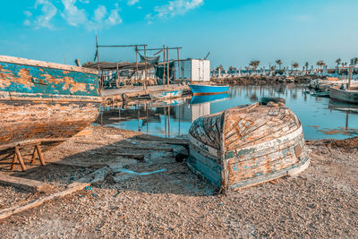 Fishing boats moored at harbor against sky