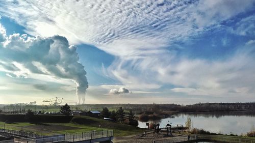 Smoke emitting from factory against sky