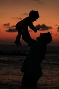 Silhouette of father and child at sunset