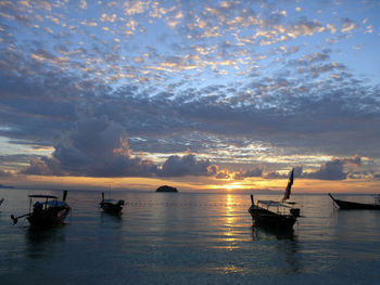 Boats in sea against sky during sunset