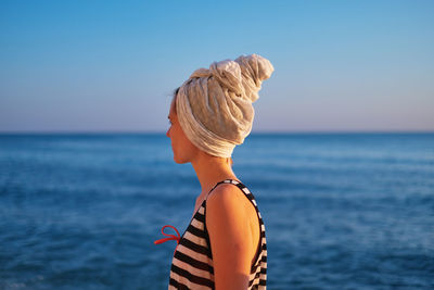 Young woman with head wrapped in towel standing at beach