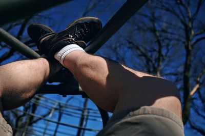 Low section of man with feet up on outdoor play equipment