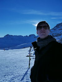 Young man standing on snow covered field against sky