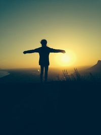 Rear view of silhouette woman jumping against sky during sunset