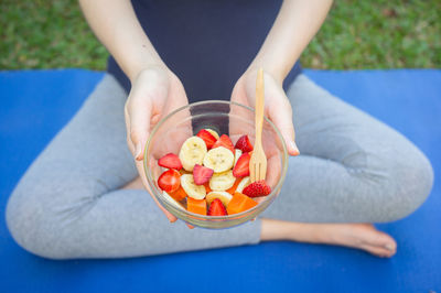 Midsection of pregnant woman eating fruits in bowl