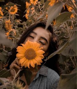 Close-up portrait of woman by sunflower