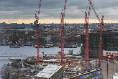 High angle view of cranes and buildings against sky