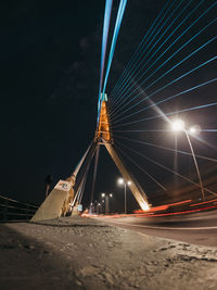 Illuminated suspension bridge against sky at night