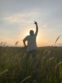 Man photographing on field against sky during sunset