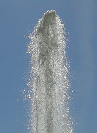 Low angle view of splashing water against blue sky