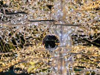 Christmas golden bauble at night with bright lights shining in the background