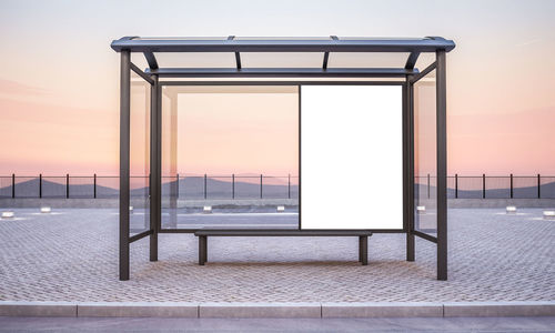 Empty chairs by railing against sky during sunset