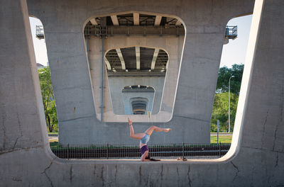 Full length of woman exercising under bridge