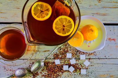 Black tea, a cup of black tea, manual squeezer with lemons. a jug of black tea and cubes of sugar