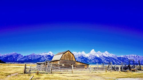 Barn on snowcapped mountains against blue sky