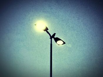 Low angle view of illuminated street light against sky