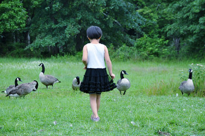 Rear view of girl standing on grassy field