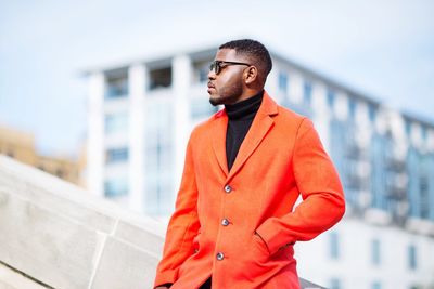 Young man looking away while standing in city